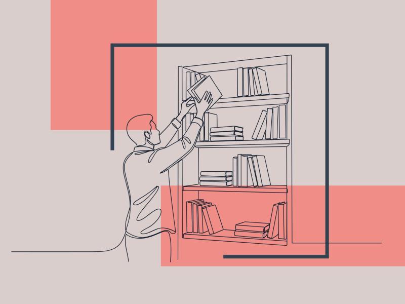 En fyr står ved en bogreol og trækker en bog ud fra øverste hylde.